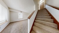 Located at 2953 W 24th Ave in Emporia, Kansas, this two-story home offers three bedrooms and two bathrooms across two floors. The layout is efficiently organized, with living and kitchen spaces complemented by a hallway and two closets for added storage.

The main floor features a kitchen equipped with wood-trimmed cabinetry, white countertops, a double-basin sink, a dishwasher, and tile flooring. Natural light enters through blinds-fitted windows, and a door provides convenient exterior access. A second kitchen space on the upper floor mirrors this functional design.

The bedrooms are carpeted throughout and finished with warm wood baseboards. The primary bedroom is a comfortable size, featuring a ceiling fan with light fixture and a window dressed with blinds that allows natural light in. Additional bedrooms are similarly appointed — one includes a pendant light fixture, while another features a window with a pleasant outdoor view of surrounding greenery.

A carpeted staircase with a wood handrail connects the two floors, leading to an open upper-level area with a window view. The bathrooms include a tub-shower combination, toilet, vanity with storage, and tile flooring. Textured ceilings are consistent throughout the home, contributing to a clean, uniform aesthetic. An electrical panel is accessible within one of the rooms.