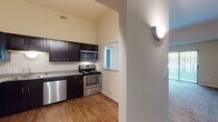 The Huron is a single-floor, 2-bedroom, 2-bathroom residence located in Wolverine Lake, Michigan. The layout is thoughtfully organized to maximize functionality across a comfortable footprint.

The kitchen is a standout feature, equipped with dark espresso cabinetry, granite-style countertops, and a full suite of stainless steel appliances including a dishwasher, range, and over-the-range microwave. Wood-style flooring runs throughout the kitchen, adding warmth to the space, while a pass-through window connects it to the adjacent living area.

The living room is notably spacious, featuring vaulted ceilings that lend an airy, open feel. Plush carpeting covers the floor, and a sliding glass door provides direct access to the outdoors while filling the room with natural light and greenery views.

The bedrooms are well-proportioned, also featuring carpeted floors and windows that bring in natural light. The two bathrooms offer distinct configurations — one includes a glass-enclosed walk-in shower with tile flooring, while the second features a full soaking tub with tiled surround, also finished with clean white tile flooring. Both bathrooms are finished in neutral tones with brushed nickel fixtures throughout.