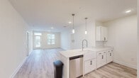 Located at 5 View Lake Dr in Clayton, NC, this single-story, 3-bedroom, 2-bathroom home offers a thoughtfully designed open-concept layout with clean, modern finishes throughout. The combined kitchen, dining, and living area serves as the heart of the home, showcasing light wood-look flooring, white shaker cabinetry with matte black hardware, quartz countertops, a farmhouse sink, and stainless steel appliances including a refrigerator, electric range, microwave, and dishwasher. Elegant pendant lighting accents the kitchen island, while large windows invite generous natural light into the living area. The spacious primary bedroom features plush carpeting, a ceiling fan, and a well-sized window with exterior views. Its ensuite bathroom includes a white vanity, a glass-door shower, and access to a walk-in closet outfitted with wire shelving. The additional bedrooms are equally bright and carpeted, offering comfortable accommodations. Both bathrooms continue the home's clean aesthetic with light flooring and white cabinetry. Further enhancing everyday functionality, the home includes a dedicated laundry room, multiple utility spaces, and five closets providing ample storage throughout.