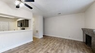 This single-story 1-bedroom, 2-bathroom unit offers a thoughtfully organized layout that maximizes every square foot. The combined living and dining area serves as the heart of the home, featuring warm wood-look flooring, a textured ceiling, and a ceiling fan overhead. A standout brick fireplace anchors one end of the living room, adding both character and warmth, while a window allows natural light to brighten the space. The living area flows seamlessly into the kitchen via a pass-through opening, which enhances the open feel between rooms. The U-shaped kitchen is well-equipped with dark cabinetry, white countertops, black appliances including a refrigerator, electric range, microwave, and dishwasher, along with a double-basin sink. The bedroom is a comfortable retreat with a ceiling fan, a sliding glass door providing outdoor views and natural light, and direct access to a closet and a full bathroom. The bathrooms feature dark vanity cabinetry and wood-look tile flooring, with one bath showcasing a full tub-shower combination finished in richly toned stone-look tile. A dedicated laundry area and a hallway entry with ceiling fan complete this practical and cohesive floor plan.