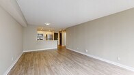 Located at 91 Valley Stream Dr in Ottawa's K2H neighbourhood, this well-appointed one-bedroom, one-bathroom unit offers a thoughtfully designed single-floor layout. The open-concept living and kitchen area forms the heart of the home, finished with light wood-tone flooring and neutral warm-beige walls that create a clean, inviting atmosphere. The kitchen is equipped with a central island featuring a undermount sink and white quartz countertop, complemented by white cabinetry, stainless steel appliances including a refrigerator, stove, built-in microwave, and dishwasher, and recessed pot lighting overhead. The adjoining living area is generously proportioned, bathed in natural light from a large corner window framing peaceful views of surrounding trees. The spacious primary bedroom is finished with the same wood-tone flooring and neutral tones, offering a serene and versatile space. The bathroom features a full soaker tub with white subway tile surround and matching wood-tone flooring. A hallway connects the principal rooms, completing the functional and efficient layout. The unit's consistent use of light finishes and natural light throughout creates a bright, cohesive living environment.