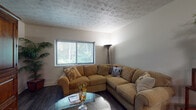 Located at 360 Broad Meadows Blvd in Columbus, Ohio, this single-floor home offers a thoughtfully designed layout with a cohesive, comfortable ambiance throughout. The living room serves as a welcoming centerpiece, featuring dark hardwood-style flooring, a textured ceiling, and a large window with horizontal blinds that frames views of lush greenery outside, filling the space with natural light. A generously sized L-shaped sectional sofa and a round glass coffee table complete the inviting atmosphere. An adjacent dining and sitting area is outfitted with a ceiling fan, additional seating, and a direct pass-through view into the kitchen, creating an open, connected feel. The kitchen is well-equipped with rich dark wood cabinetry, striking granite countertops, a stainless steel sink, and tile flooring, providing both style and functionality. The bedroom offers a cozy retreat with carpeted flooring, a textured ceiling, and a window that allows in natural light. The full bathroom features slate-toned tile flooring, dark wood cabinetry with a white countertop vanity, a large mirror, and a tub-shower combination, delivering a clean and functional design. Throughout the home, neutral wall tones and consistent finishes create a unified and comfortable living environment.