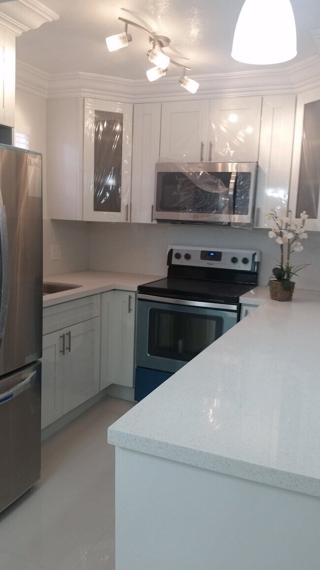 Clean white modern kitchen w/quartz & SS appliances - 2500 NE 9th St