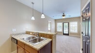 This thoughtfully designed one-bedroom, one-bathroom residence offers a functional and comfortable layout across a single floor. The kitchen is a standout feature, outfitted with warm cherry wood cabinetry, granite countertops with a tile backsplash, and a full suite of stainless steel appliances including a refrigerator, range, and built-in microwave. A peninsula with pendant lighting bridges the kitchen to the open living area, which is finished with plush carpeting, a ceiling fan, and multiple windows that invite natural light throughout the day. A glass door provides direct access to an outdoor area, enhancing the sense of openness. The bedroom is a comfortable retreat, carpeted and well-lit by a large window with outdoor views, and also features a ceiling fan. A dedicated closet provides convenient storage adjacent to the bedroom. The bathroom is cleanly appointed with tile flooring, a tiled tub-shower surround featuring a decorative accent border, and classic fixtures. Light-toned walls and consistent finishes throughout the residence create a cohesive and welcoming ambiance, making this a practical and inviting living space.