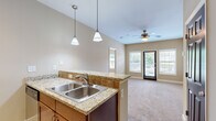 This thoughtfully designed one-bedroom, one-bathroom residence offers a functional and comfortable layout across a single floor. The kitchen is a standout feature, outfitted with warm cherry wood cabinetry, granite countertops with a tile backsplash, and a full suite of stainless steel appliances including a refrigerator, range, and built-in microwave. A peninsula with pendant lighting bridges the kitchen to the open living area, which is finished with plush carpeting, a ceiling fan, and multiple windows that invite natural light throughout the day. A glass door provides direct access to an outdoor area, enhancing the sense of openness. The bedroom is a comfortable retreat, carpeted and well-lit by a large window with outdoor views, and also features a ceiling fan. A dedicated closet provides convenient storage adjacent to the bedroom. The bathroom is cleanly appointed with tile flooring, a tiled tub-shower surround featuring a decorative accent border, and classic fixtures. Light-toned walls and consistent finishes throughout the residence create a cohesive and welcoming ambiance, making this a practical and inviting living space.