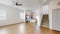 Located in Castle Pines, Colorado, this contemporary two-story home offers four bedrooms and three bathrooms across two well-designed floors. The main level features an open-concept living area with light hardwood-style flooring, recessed lighting, and a ceiling fan, creating a bright and airy atmosphere. Natural light pours in through multiple windows, enhancing the clean, modern aesthetic defined by crisp white walls and simple, elegant finishes.

The kitchen is a standout feature, boasting light wood cabinetry, a white subway tile backsplash, stainless steel appliances, and a spacious island with a sleek gray quartz countertop — ideal for both cooking and casual dining. A large window adjacent to the kitchen floods the space with natural light and provides views of the outdoors.

A carpeted staircase leads to the upper level, where the primary bedroom offers a generous layout with hardwood-style flooring and a well-appointed en-suite bathroom. The primary bath features light wood cabinetry with dark hardware, quartz countertops, hardwood-style flooring, and a glass-enclosed tile shower. Additional bedrooms are comfortably sized with plush carpet and natural light from bright windows. The bathrooms include a clean, tiled tub-shower combination, maintaining the home's consistent modern style throughout.