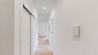 Located at 36 N Narberth Ave in Narberth, PA, this thoughtfully designed two-bedroom, two-bathroom residence offers a cohesive blend of modern aesthetics and functional living across a single floor. The open-concept living and kitchen area serves as the centerpiece of the home, featuring light-toned wide-plank hardwood floors, recessed lighting, and expansive black-framed windows that frame views of the surrounding streetscape and fill the space with natural light. The kitchen is equipped with white shaker cabinetry, stainless steel appliances, dark granite countertops, and a striking black marble waterfall island accented by pendant lighting.

Both bedrooms continue the warm hardwood flooring and neutral palette, with large black-framed windows providing natural light and wooded views. The primary bedroom features elevated ceilings and a dedicated closet. The secondary bedroom includes a built-in closet with panel doors.

Each bathroom is finished with bold gray marble-patterned tile flooring. One bathroom features a white vanity with an integrated sink and a framed marble-accented mirror, while the other offers a glass-enclosed walk-in shower with marble-style tile surround. A hallway connects the private areas of the residence, completing this well-appointed single-level layout.