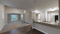Located at 8720 Knickerbocker Way in Indianapolis, Indiana, this multi-story home offers five bedrooms and three bathrooms spread across three floors, providing generous living space for residents. The main level features an open-concept kitchen and living area, where dark-stained wood cabinetry, granite countertops, and stainless steel appliances make a strong impression. A breakfast bar with a built-in sink connects the kitchen to the living space, which features rich hardwood-style flooring and an arched entryway leading to a carpeted living area filled with natural light from large windows. The living room showcases vaulted ceilings that add a sense of openness and volume to the space. Bedrooms are carpeted and include ceiling fans and windows that allow ample natural light, with the primary bedroom offering a notably spacious layout. The three bathrooms are well-appointed with granite-topped vanities, dark wood cabinetry, wood-style flooring, and tiled shower and tub combinations. A dedicated laundry room on the upper floor houses a full-size washer and dryer. Carpeted staircases with wood handrails connect all three levels, complementing the home's warm, neutral color palette throughout.