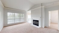 This single-floor residence offers a well-designed layout that balances comfort and functionality across its living spaces. The living room serves as the central highlight, featuring vaulted ceilings that lend an airy, open feel and a classic white-mantled fireplace with tile surround as a focal point. Large windows fitted with blinds allow abundant natural light to fill the room, which is finished with plush neutral carpeting. Architectural column detailing and a decorative ledge add subtle character to the space.

The kitchen is thoughtfully appointed with white cabinetry, granite-toned countertops, a subway tile backsplash, and stainless steel appliances including an electric range, microwave, and dishwasher. An adjacent dining area benefits from oversized windows overlooking greenery, enhancing the sense of connection to the outdoors. Light wood-style flooring runs throughout the kitchen and dining areas.

The bedrooms are carpeted and well-lit, with crown molding details and ceiling fans adding comfort. The bathrooms include a full bath with a soaking tub and a distinctive red and white tile surround, and a second bath with a white vanity and wood-look flooring. Throughout, the neutral palette and clean finishes create a cohesive, inviting atmosphere.