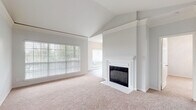 This single-floor residence offers a well-designed layout that balances comfort and functionality across its living spaces. The living room serves as the central highlight, featuring vaulted ceilings that lend an airy, open feel and a classic white-mantled fireplace with tile surround as a focal point. Large windows fitted with blinds allow abundant natural light to fill the room, which is finished with plush neutral carpeting. Architectural column detailing and a decorative ledge add subtle character to the space.

The kitchen is thoughtfully appointed with white cabinetry, granite-toned countertops, a subway tile backsplash, and stainless steel appliances including an electric range, microwave, and dishwasher. An adjacent dining area benefits from oversized windows overlooking greenery, enhancing the sense of connection to the outdoors. Light wood-style flooring runs throughout the kitchen and dining areas.

The bedrooms are carpeted and well-lit, with crown molding details and ceiling fans adding comfort. The bathrooms include a full bath with a soaking tub and a distinctive red and white tile surround, and a second bath with a white vanity and wood-look flooring. Throughout, the neutral palette and clean finishes create a cohesive, inviting atmosphere.