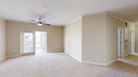 Located at 131 Stillwater Landing Way in Sneads Ferry, NC, this single-story, 3-bedroom, 2-bathroom home offers a comfortable and practical layout ideal for everyday living. The open-concept living room and kitchen area serves as the heart of the home, with plush carpeting, crown molding, a ceiling fan, and sliding glass doors that invite natural light and provide access to an outdoor space. The kitchen features warm honey-toned cabinetry, light stone countertops with a breakfast bar, and black appliances including a refrigerator, range, and over-the-range microwave. Each of the three bedrooms is carpeted and equipped with a ceiling fan, offering a comfortable retreat. The bedrooms benefit from multiple windows that fill the rooms with natural light, and several include walk-in closets with wire shelving systems for ample storage. The bathrooms are finished with tile flooring, warm wood vanities, and light countertops, with one bathroom featuring a full tub-shower combination. A dedicated laundry room with tile flooring houses a full-size washer and dryer along with overhead shelving. Throughout the home, neutral beige tones create a clean, cohesive aesthetic.