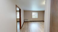 Located at 2620-2626 Chippewa St in St. Louis, MO, this one-bedroom, one-bathroom unit offers a practical and well-organized layout across a single floor. The space features light wood-style laminate flooring throughout, complemented by neutral beige walls and dark baseboards that provide a clean, cohesive aesthetic.

The bedroom is a comfortable, well-proportioned room highlighted by a large window that invites natural light and offers views of the surrounding neighborhood. A wall-mounted PTAC unit provides climate control, and the room includes ample wall space for furniture arrangement.

A connecting hallway links the bedroom to the rest of the unit, leading toward a kitchen area visible in the background, which features warm wood cabinetry and standard appliances including a refrigerator. The hallway provides a natural transition between the living spaces.

The bathroom is finished with warm wood-tone cabinetry, a white countertop vanity with an integrated sink, and a chrome towel bar. A mirrored medicine cabinet adds both function and brightness to the space.

Overall, the unit presents a clean, move-in-ready environment with consistent finishes throughout. Its straightforward, efficient layout makes it a practical choice for those seeking comfortable living in the Chippewa Street corridor of St. Louis.