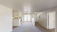 This single-story unit presents a practical and well-organized layout with clearly defined living spaces throughout. The open-concept living and dining area is generously proportioned, featuring soft gray carpet, a ceiling fan, and a textured popcorn ceiling. A set of double windows allows natural light to fill the space, while a half-wall partition separates the living area from the kitchen.

The galley-style kitchen is efficiently designed, offering ample white cabinetry both above and below granite-style laminate countertops, a double stainless steel sink, a white refrigerator, and a range. Wood-look flooring runs underfoot, providing a durable, easy-to-maintain surface.

Two bedrooms are each carpeted and finished with neutral tones, textured ceilings, and standard flush-mount lighting. Both rooms offer closet access, with one bedroom featuring a walk-in closet for additional storage.

The bathrooms are appointed with granite-style laminate vanity countertops, white cabinetry, large mirrors, and wood-look flooring. One bathroom includes a separate water closet with a tub-shower combination. The overall aesthetic is clean and neutral, offering a functional and move-in ready living environment.