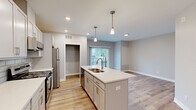 Located at 2329 SE Timberbrook Dr in Grand Rapids, MI, this one-bedroom, one-bathroom unit offers a thoughtfully designed open-concept floor plan with modern finishes throughout. Light-toned luxury vinyl plank flooring runs seamlessly across the entire space, creating a clean and cohesive aesthetic.

The kitchen is a standout feature, showcasing crisp white cabinetry, a classic subway tile backsplash, quartz countertops, and stainless steel appliances including a gas range, microwave, and refrigerator. A central island with a double-basin sink and elegant pendant lighting above serves as both a functional workspace and a natural gathering point that flows into the open living area.

The living room receives natural light through a sliding glass door, offering outdoor access and brightening the space. Recessed lighting throughout supplements the natural light for a well-lit environment. The bedroom is a comfortable, well-proportioned room with the same plank flooring and neutral wall tones, accompanied by a dedicated closet fitted with wire shelving and hanging rods for organized storage.

The bathroom features a white vanity with ample drawer storage, a backlit mirror, and matching light finishes that maintain the unit's clean, contemporary feel. In-unit laundry hookups are also present, adding everyday convenience to this well-appointed home.