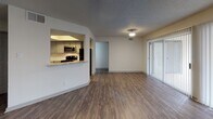 Located at 1720 John West Rd in Dallas, Texas, this single-floor residence offers a well-appointed layout with a variety of functional and updated interior finishes. The living area makes a strong first impression with rich, dark wood-look flooring, a ceiling fan with light fixture, a textured ceiling, and a tile-surround fireplace that serves as a natural focal point. An adjacent open area connects seamlessly to the pass-through kitchen, which features gray cabinetry, granite-style countertops, white subway tile backsplash, a stainless steel microwave, black appliances including a dishwasher and electric range, and a window above the sink that brings in natural light. Sliding glass doors in the secondary living area provide access to the outdoors. The bathrooms are finished with granite-top vanities, large mirrors, and a tiled shower-tub combination. The bedrooms are carpeted for comfort and are generously sized, each equipped with a ceiling fan and multiple windows that flood the rooms with natural light and offer views of the surrounding greenery. The overall aesthetic is clean, neutral, and move-in ready, reflecting thoughtful updates throughout the single-story layout.