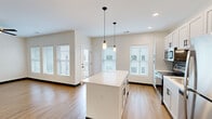 Located at 4591 McRee Ave in St. Louis, Missouri, this well-designed 2-bedroom, 2-bathroom home offers a clean, modern aesthetic across a single thoughtfully laid-out floor. The open-concept kitchen and living area serves as the heart of the home, featuring white shaker cabinetry, a tiled backsplash, stainless steel appliances, and a central island with pendant lighting overhead. Light wood-tone flooring runs continuously throughout, complementing the neutral color palette and dark accent trim. Multiple windows fitted with horizontal blinds allow generous natural light to fill each room. Both bedrooms are comfortably sized — the primary bedroom offers a spacious walk-in closet with wire shelving — and each room is equipped with a ceiling fan. The two bathrooms are finished in a contemporary style; one features a frameless sliding glass shower enclosure with white subway tile and black matte hardware. A dedicated laundry closet houses a stacked washer and dryer alongside a water heater, keeping utilities neatly contained. The home also includes a separate closet for additional storage. With its fresh construction detailing, cohesive design, and practical layout, this residence delivers modern comfort in a convenient St. Louis location.