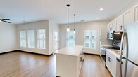 Located at 4591 McRee Ave in St. Louis, Missouri, this well-designed 2-bedroom, 2-bathroom home offers a clean, modern aesthetic across a single thoughtfully laid-out floor. The open-concept kitchen and living area serves as the heart of the home, featuring white shaker cabinetry, a tiled backsplash, stainless steel appliances, and a central island with pendant lighting overhead. Light wood-tone flooring runs continuously throughout, complementing the neutral color palette and dark accent trim. Multiple windows fitted with horizontal blinds allow generous natural light to fill each room. Both bedrooms are comfortably sized — the primary bedroom offers a spacious walk-in closet with wire shelving — and each room is equipped with a ceiling fan. The two bathrooms are finished in a contemporary style; one features a frameless sliding glass shower enclosure with white subway tile and black matte hardware. A dedicated laundry closet houses a stacked washer and dryer alongside a water heater, keeping utilities neatly contained. The home also includes a separate closet for additional storage. With its fresh construction detailing, cohesive design, and practical layout, this residence delivers modern comfort in a convenient St. Louis location.