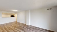 This single-floor unit offers a well-organized layout with a clean, neutral aesthetic that flows naturally from room to room. The open living area is finished with wood-look plank flooring and a textured ceiling, creating a bright and airy atmosphere. A sliding glass door leads to a private balcony, bringing in natural light and outdoor views of surrounding greenery. The space connects seamlessly to the kitchen, which features white shaker cabinetry, granite-style countertops, a tile backsplash, and a full suite of stainless steel appliances including a refrigerator, range, and built-in microwave. Recessed lighting illuminates the kitchen's functional workspace. The bedrooms are carpeted for comfort and offer generous wall space, with one room benefiting from a large window framing pleasant outdoor views. A hallway provides access to a closet and connects the sleeping areas to the rest of the unit. The bathroom is finished with light tile flooring, a granite-topped vanity, and a full soaking tub with shower. Throughout the unit, white walls and consistent finishes contribute to a cohesive, move-in-ready environment.