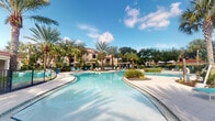 Located at 4600 Portofino Way in West Palm Beach, Florida, this outdoor amenity space captures the essence of resort-style living in South Florida. The centerpiece is a generously sized, freeform lagoon pool with crystal-clear turquoise water that winds through a beautifully landscaped setting. The pool's organic, curved design creates a relaxed, tropical atmosphere reminiscent of a luxury resort destination.

Surrounding the pool, a broad, light-toned paved deck provides ample space for lounging, lined with teal-accented chaise lounge chairs and shaded by pergolas and large umbrellas. Lush tropical landscaping — including tall swaying palm trees, manicured shrubs, and tropical plantings — frames the space, offering both visual appeal and natural shade.

In the background, the Mediterranean-inspired residential architecture features warm stucco facades with terracotta-accented rooflines, complementing the overall Portofino-themed aesthetic. The open sky above floods the entire area with abundant natural Florida sunshine, enhancing the bright, inviting ambiance. This outdoor space offers a tranquil, resort-caliber retreat ideal for relaxation and recreation, set within the vibrant community of West Palm Beach.