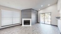 Located at 11025 S 51st St in Phoenix, AZ, this two-bedroom, one-bathroom home offers a well-designed single-level layout with a range of functional features throughout. The living room serves as the focal point of the home, showcasing a striking floor-to-ceiling gray shiplap accent wall framing a wood-burning fireplace with a white surround. Light wood-style luxury vinyl flooring runs throughout the main living areas, complemented by neutral gray walls and recessed lighting. A sliding glass door floods the space with natural light and provides outdoor access. The kitchen features a pass-through breakfast bar, white cabinetry, stainless steel appliances including a range and microwave, and a utility sink. Both bedrooms are carpeted and equipped with ceiling fans, offering a comfortable retreat. The spacious primary bedroom includes a walk-in closet with built-in shelving and rod storage, as well as an en-suite bathroom access. The second bedroom also benefits from a dedicated closet. The full bathroom is outfitted with a soaking tub and shower combo with clean white surroundings. Textured ceilings are present throughout, adding a classic finish to this well-appointed Phoenix home.