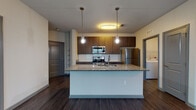 Located at 2509 Cattlemen Rd in Sarasota, Florida, this single-floor residence offers a thoughtfully designed open-concept layout that seamlessly connects the kitchen, dining, and living areas. Rich, dark hardwood-style flooring runs throughout the main living spaces, complemented by neutral-toned walls that create a clean, contemporary aesthetic.

The kitchen is a standout feature, centered around a large island with granite countertops and an undermount sink illuminated by pendant lighting. Dark espresso cabinetry lines the walls, paired with a white subway tile backsplash and a full suite of stainless steel appliances, including a range, over-the-range microwave, and refrigerator. A dedicated laundry area is conveniently accessible nearby.

The spacious living area benefits from multiple windows fitted with horizontal blinds, allowing natural light to filter in, and is finished with a ceiling fan overhead. A glass-panel exterior door adds additional brightness to the room.

The bedrooms are carpeted for comfort, each equipped with ceiling fans and windows that invite natural light. The bathroom features granite-topped dark wood vanities with undermount sinks, wood-look tile flooring, a glass-enclosed walk-in shower with white tile surround, and brushed nickel fixtures throughout, delivering a polished, cohesive finish.