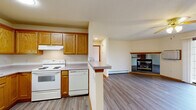 Located at 201 Air Park Dr in Watertown, Wisconsin, this single-floor, one-bedroom, one-bathroom unit offers a practical and comfortable layout with thoughtful finishes throughout. The open-concept living and dining area is a highlight of the space, featuring durable luxury vinyl plank flooring, a ceiling fan, and a corner gas fireplace framed with warm wood trim. A large sliding glass door floods the area with natural light and provides views of the surrounding green lawn. The kitchen is well-appointed with oak cabinetry, ample counter space, a full suite of white appliances including a refrigerator, electric range, and dishwasher, and a peninsula that connects it to the main living area. The generously sized bedroom is carpeted for comfort, includes a ceiling fan, a dedicated window for natural light, and access to multiple closets, including a spacious walk-in closet outfitted with built-in shelving and hanging rods. The full bathroom features oak vanity cabinetry, a lighted mirror, and a tub-shower combination with vinyl flooring. Additional conveniences include an in-unit laundry area, baseboard heating throughout, and ample closet storage. The entry foyer provides a welcoming transition into the living space.