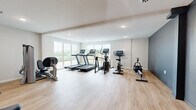 Located at 3425 Eischen Ct in Duluth, MN, this fitness center offers a thoughtfully designed workout facility spread across a single floor. The space is divided into two primary areas: a main exercise room and an accessible restroom.

The main workout area features light hardwood-style flooring and crisp white walls accented by a bold slate-blue feature wall, creating a clean and motivating atmosphere. Large windows along one side flood the space with natural light while offering views of the surrounding landscape, enhancing the overall workout environment. Recessed ceiling lighting provides additional illumination throughout.

The fitness area is well-appointed with a comprehensive range of equipment, including multiple treadmills, elliptical trainers, a stationary bike, a rowing machine, a multi-function cable/strength training machine, a weight bench, and additional resistance equipment — offering a full suite of cardio and strength training options.

The adjacent restroom is ADA-accessible, featuring white subway tile wainscoting, a gray concrete-style floor, stainless steel grab bars, and a wall-mounted vanity with wood accents. The space is clean, functional, and designed with accessibility in mind.

Overall, the facility presents a modern, well-maintained environment suited for a diverse range of fitness activities.
