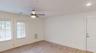 This thoughtfully designed single-floor unit offers a comfortable and functional layout across a well-utilized footprint. The spacious living room features warm wood-look flooring, a ceiling fan with light fixture, and a glass-panel door that floods the space with natural light while providing access to the outdoors. Adjacent to the living area, the dining space is accented by an elegant chandelier and opens directly to the kitchen via a breakfast bar peninsula. The kitchen is well-equipped with grey shaker-style cabinetry, granite-look countertops, a double-basin sink, and a full suite of stainless steel appliances including a refrigerator, electric range, built-in microwave, and dishwasher. A skylight enhances the brightness of the kitchen area. The bedroom offers plush carpeting and a generously sized walk-in closet with built-in shelving and rods. The full bathroom includes a tub/shower combo with integrated shelving, a granite-topped vanity, and wood-look tile flooring. Completing the unit is a dedicated laundry area with a stacked washer and dryer. Clean white walls and consistent finishes throughout lend the space a cohesive, modern aesthetic.