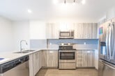 Located at 45 Yarmouth St in Guelph, Ontario, this well-appointed 2-bedroom, 2-bathroom unit offers a thoughtfully designed single-level layout with contemporary finishes throughout. Light-toned luxury vinyl plank flooring runs seamlessly across the entire space, complementing the neutral palette of crisp white trim and warm beige walls.

The open-concept kitchen and living area serves as the heart of the unit. The kitchen is outfitted with modern light wood cabinetry, a tile backsplash, quartz countertops, a double undermount sink, and a full suite of stainless steel appliances. The living room is bright and airy, anchored by floor-to-ceiling windows and a glass door that opens onto a private balcony offering sweeping treetop views of the surrounding Guelph landscape.

A central hallway connects the two bedrooms, each featuring generous proportions and large windows that invite abundant natural light. The spacious primary bedroom enjoys its own elevated cityscape view. Both bathrooms are finished in a clean, contemporary style with wood-grain vanities, quartz countertops, undermount sinks, and large mirrors.

Adding to everyday convenience, the unit includes two dedicated laundry areas, each equipped with a stacked washer and dryer. The overall design is modern, functional, and move-in ready.