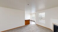 Located at 7680 SW 74th Ave in Portland, Oregon, this one-bedroom, one-bathroom unit offers a practical and comfortable layout across a single floor. The living room serves as the heart of the home, featuring plush carpeting, neutral walls, and a tile-surround fireplace that adds warmth and character to the space. Natural light filters in through windows with blinds, creating a bright and welcoming atmosphere.

The kitchen is equipped with white cabinetry accented by warm wood trim, a coil-top electric range, a full-size refrigerator, and a tile backsplash. Light hardwood-style flooring runs through the kitchen and dining area, which also benefits from a door leading directly to a private outdoor deck — a convenient feature for enjoying the Pacific Northwest outdoors.

The bedroom is generously sized with soft carpeting, a large sliding double-door closet offering ample storage, and a window that allows in natural light. The bathroom features a wood-trimmed vanity with a white countertop, an illuminated mirror, and dark hardwood-style flooring. A dedicated in-unit laundry area with overhead shelving adds everyday convenience. Throughout the unit, warm wood trim provides a cohesive, inviting aesthetic.