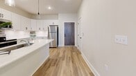 Located in the Shadow Creek community of Jackson, Tennessee, this single-story space showcases a clean, modern design highlighted by consistent light wood-look luxury vinyl plank flooring and a neutral, warm-white color palette carried throughout every room. The open-concept kitchen serves as a focal point, featuring crisp white shaker-style cabinetry, white quartz countertops, a peninsula with pendant lighting overhead, and stainless steel appliances including a refrigerator, range, and microwave. A full-height pantry cabinet provides ample storage, while recessed lighting supplements the natural brightness of the space.

The living areas are bright and versatile, with generous wall space and large windows fitted with horizontal blinds that allow for controlled natural light. The bedroom spaces maintain the same cohesive aesthetic, with neutral walls, white baseboards, and wood-look flooring. The bathroom includes a dark-toned vanity with white countertop, wood-look tile flooring, a walk-in shower, and access to a walk-in closet. Throughout the unit, Shaker-style interior doors with matte black hardware add a contemporary touch. The overall ambiance is modern, clean, and move-in ready.