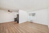 Located at 425 E Bradley Ave in El Cajon, CA, this single-story, one-bedroom, one-bathroom unit offers a clean and functional layout finished with light wood flooring and crisp white walls throughout. The open living and dining area is bright and airy, with a large window fitted with blinds allowing natural light to fill the space. A ceiling fan adds comfort overhead, while a wall-mounted HVAC unit provides climate control. The kitchen is well-appointed with white upper cabinets, gray lower cabinets, granite countertops, a white subway tile backsplash, and a full suite of stainless steel appliances including a range, microwave, dishwasher, and refrigerator. A window above the sink brings in additional natural light. The spacious primary bedroom features a sliding-door closet, a window with blinds, and textured ceiling detailing consistent throughout the unit. A second closet provides additional storage. The bathroom is finished with white subway tile surrounding a tub-shower combination, brushed nickel fixtures, and a window for ventilation. A hallway connects the living spaces to the private areas of the unit, creating a straightforward and efficient floor plan.