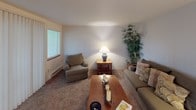 This single-floor residence at 9215–9465 S 235th Pl in Kent, Washington, offers a practical and comfortable layout across several well-defined living spaces. The living room provides a relaxed atmosphere with plush carpeting, a large window fitted with blinds that allows natural light to filter in, and ample space for seating arrangements. Adjacent to the living room, the dedicated dining area features carpet flooring, a window overlooking greenery, and an overhead chandelier that adds a touch of warmth to mealtimes.

The galley-style kitchen is efficiently designed with white cabinetry lining both sides, light countertops, white appliances including a range and refrigerator, a dishwasher, and wood-look vinyl flooring that provides a clean, durable surface underfoot.

The unit includes multiple bedrooms, each carpeted and equipped with windows that bring in natural light and outdoor views. The bedrooms offer functional closet storage, and their neutral wall tones contribute to a calm, restful environment.

The bathroom features wood-look vinyl flooring, a vanity with a sink, and a clean, bright finish throughout. The space as a whole presents a straightforward, livable design well-suited to everyday comfort.