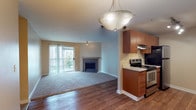 This single-floor residence offers a thoughtfully designed open-concept layout that seamlessly connects the kitchen, dining, and living areas. The living room is anchored by a classic fireplace and features plush carpeting, while sliding glass doors lead to a private balcony, filling the space with natural light and outdoor views. Rich hardwood flooring transitions from the entryway and dining area into the kitchen zone, adding warmth and visual contrast.

The galley-style kitchen is well-equipped with warm wood cabinetry, light stone countertops, stainless steel appliances including a range and refrigerator, a double stainless steel sink, and track lighting overhead — providing both functionality and style.

The bedrooms are carpeted and generously sized, each featuring windows that bring in natural light and access to closet space. The bathrooms are finished with wood-toned vanities, light stone countertops, large mirrors with vanity lighting, and wood-look flooring.

A dedicated laundry area houses a full-size washer and dryer alongside a water heater, adding everyday convenience. Throughout the residence, neutral warm tones on the walls create a cohesive, inviting atmosphere suited to a variety of interior styles.