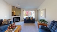 Located at 7808 North Morton Street in Spokane, Washington, this single-floor home offers a thoughtfully laid-out interior with a warm, neutral color palette throughout. The living room serves as the heart of the home, anchored by a sleek, built-in fireplace and framed by large windows that invite abundant natural light and views of mature trees outside. An open pass-through connects the living area to the elevated entry zone, adding architectural interest and visual depth to the space.

The kitchen is efficiently designed with ample light-toned cabinetry, generous counter space, a full suite of appliances including a dishwasher, electric range, and refrigerator, and bright overhead lighting. Soft carpeting in the kitchen area adds a distinctive warmth to the room.

The bedrooms are comfortably sized with plush carpeting and good natural light. One bedroom is well-suited as a nursery, while another serves as a primary bedroom with direct access to a private bathroom. The bathrooms are clean and functional — one features a tiled tub-shower combination, while another offers a walk-in shower, a wide vanity with ample storage, and patterned tile flooring. Overall, the home presents a cohesive, comfortable living environment ideal for everyday living.