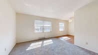 This single-floor unit offers a practical and functional layout, accommodating four bedrooms, one bathroom, a living room, a kitchen, and a connecting hallway. The living area is bright and welcoming, featuring a combination of plush carpet and warm hardwood flooring. Multiple windows fitted with blinds allow generous natural light to fill the space, while a ceiling fan with a light fixture adds both comfort and a clean aesthetic. The transition between carpet and hardwood creates a natural visual distinction between the living and dining or entry zones.

Each bedroom is carpeted and features neutral wall tones, providing a clean, move-in-ready canvas. The bedrooms are well-proportioned, with the primary bedroom offering a notably generous footprint. Bedrooms are equipped with closets featuring louvered bifold doors, built-in shelving, and hanging rods for organized storage. Windows in the bedrooms offer views of the surrounding exterior greenery.

The bathroom is clean and straightforward, outfitted with a full-size bathtub and shower combination in an all-white surround, accompanied by standard fixtures. The kitchen and hallway round out the layout, connecting the rooms efficiently. The space is characterized by its light neutral color palette, consistent flooring materials, and practical storage solutions throughout.