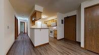 Located at 3164 Muir Field Rd in Madison, Wisconsin, this single-floor unit offers a practical and well-organized layout throughout. The kitchen is a central highlight, featuring warm honey-toned wood cabinetry extending to the upper walls, granite-look countertops, and white appliances including a range, microwave, refrigerator, and dishwasher. A peninsula with a breakfast bar separates the kitchen from the adjacent living area, creating an open and connected feel. The living and dining areas feature durable wood-look plank flooring and ceiling fans, providing a comfortable, everyday living environment. A hallway leads to the private areas of the unit, where carpeted bedrooms offer a quieter, softer setting. The bedrooms are bright, with large windows framing lush green tree views and baseboard heating for year-round comfort. Closet storage is conveniently integrated near the entry. The bathroom is clean and functional, featuring a full tub-shower combination, a single-sink vanity with wood cabinetry, and wood-look flooring. Throughout the unit, consistent warm wood trim and neutral wall tones create a cohesive and inviting atmosphere suited for comfortable everyday living.