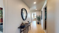 Located at 700 Broadway in Santa Monica, CA, this well-appointed 2-bedroom, 2-bathroom residence offers a refined modern living experience across a single floor. The entryway sets an elegant tone with light hardwood flooring, recessed lighting, and a welcoming hallway that connects each space seamlessly.

The open-concept kitchen and living area serves as the heart of the home. The kitchen features light wood flat-panel cabinetry extending to the ceiling, a sleek induction cooktop, stainless steel oven, white quartz countertops, and a central island with bar seating — complemented by an adjacent pantry for additional storage. The living room is defined by dramatic floor-to-ceiling curved glass windows that flood the space with natural light and frame panoramic Santa Monica city views.

The spacious primary bedroom offers direct access to the outdoors through large windows overlooking tree-lined streets, with tile flooring and generous closet space. Both bathrooms are finished in polished marble-style tile, with one featuring a glass-enclosed walk-in shower and the other offering a combined soaking tub and shower. A second bedroom with warm terracotta-toned walls adds a distinct character to the residence. Throughout, hardwood floors, recessed lighting, and clean architectural lines create a cohesive, contemporary ambiance.
