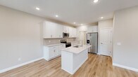 Located in Sylvania, Ohio, this two-story home offers a well-designed layout spread across two floors. The main level features an open-concept kitchen and living room highlighted by light hardwood flooring, recessed lighting, and large windows that invite abundant natural light and backyard views. The kitchen is appointed with crisp white shaker cabinetry, a subway tile backsplash, light stone countertops, stainless steel appliances, and a central island with an integrated sink — ideal for both everyday cooking and entertaining. A sliding glass door in the living area provides direct access to the backyard. The main level also includes an attached garage with an automatic opener and built-in storage closet, along with convenient hallway access.

Upstairs, the generously sized primary bedroom features plush carpeting, a ceiling fan, a walk-in closet, and a private en-suite bathroom with a white vanity. Two additional bedrooms offer comfortable accommodations with ceiling fans and hardwood-style flooring. A dedicated laundry room on the upper level is equipped with a full-size washer and dryer and overhead cabinetry for added storage. Two closets, multiple hallways, and a well-placed staircase complete the functional and cohesive floor plan throughout this move-in-ready home.