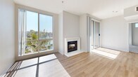 Located at 13970 Panay Way in the heart of Marina del Rey, CA, this one-bedroom, one-bathroom residence offers a well-designed layout with an open-concept living and kitchen area, a spacious bedroom, a full bathroom, a pantry, and two closets. The living room is a standout, featuring light wood-style flooring, a crisp white fireplace, and expansive floor-to-ceiling windows that flood the space with natural light. A sliding glass door opens to a private balcony showcasing breathtaking, unobstructed views of the marina, complete with sailboats, palm trees, and sparkling blue water under the Southern California sun. The kitchen is efficiently laid out with warm wood cabinetry, white countertops, a gas range, and a dedicated pantry for added storage. The bedroom is carpeted and generously sized, with marina-facing windows that continue the scenic views, two closets providing ample storage, and direct access to the full bathroom. The bathroom features warm wood vanity cabinetry, white countertops, and a shower-tub combination with light wood-style flooring. The overall aesthetic is clean, bright, and contemporary, with a neutral palette throughout that creates a calm and inviting coastal ambiance.