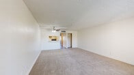 Located at 33 N Wilmot Rd in Tucson, AZ, this single-story residence offers two bedrooms and two full bathrooms within a well-organized floor plan. The combined kitchen and living room serves as the heart of the home, with the kitchen featuring a galley-style layout equipped with wood-toned cabinetry, a stainless steel sink, ample counter space, and white appliances including a refrigerator, electric range, and dishwasher. Wood-style flooring runs through the kitchen, while plush carpet extends throughout the living areas and bedrooms. The living room is bright and open, highlighted by a ceiling fan, a sliding glass door leading to an outdoor balcony with exterior views, and a pass-through window connecting to the kitchen. A secondary window at the front of the unit brings in additional natural light. Both bedrooms are generously proportioned, each featuring sliding-door closets with built-in shelving and carpet flooring. The two bathrooms are well-appointed with wood-toned vanities, granite-style countertops, and wood-style flooring. One bathroom includes a walk-in shower with a glass sliding door, while the second features a shower-tub combination. Textured ceilings are consistent throughout, and a hallway with closet access connects the private areas of the home.
