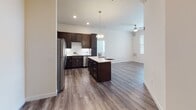 This single-floor residence showcases a thoughtfully designed open-concept layout connecting the kitchen and living area. The kitchen is a standout feature, equipped with rich dark-espresso cabinetry, a full suite of stainless steel appliances including a refrigerator, range, microwave, and dishwasher, and a white subway tile backsplash. A generously sized center island with a light quartz countertop provides additional workspace and casual dining space, illuminated by a stylish pendant light overhead. Wood-look plank flooring runs throughout the main living areas, lending a clean, contemporary aesthetic.

The open living area benefits from multiple windows fitted with blinds, allowing ample natural light, and is equipped with a ceiling fan. A sliding glass door leads to an outdoor area, further enhancing the brightness of the space.

The bedrooms feature soft carpeting and multiple windows offering outdoor views, providing comfortable and well-lit retreats. The bathroom includes a combination tub and shower, a dark-cabinetry vanity with a light countertop, and hardwood-style flooring. The primary suite connects to a walk-in closet with built-in wire shelving, offering practical storage throughout.