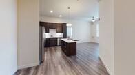 This single-floor residence showcases a thoughtfully designed open-concept layout connecting the kitchen and living area. The kitchen is a standout feature, equipped with rich dark-espresso cabinetry, a full suite of stainless steel appliances including a refrigerator, range, microwave, and dishwasher, and a white subway tile backsplash. A generously sized center island with a light quartz countertop provides additional workspace and casual dining space, illuminated by a stylish pendant light overhead. Wood-look plank flooring runs throughout the main living areas, lending a clean, contemporary aesthetic.

The open living area benefits from multiple windows fitted with blinds, allowing ample natural light, and is equipped with a ceiling fan. A sliding glass door leads to an outdoor area, further enhancing the brightness of the space.

The bedrooms feature soft carpeting and multiple windows offering outdoor views, providing comfortable and well-lit retreats. The bathroom includes a combination tub and shower, a dark-cabinetry vanity with a light countertop, and hardwood-style flooring. The primary suite connects to a walk-in closet with built-in wire shelving, offering practical storage throughout.