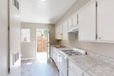 Located at 19007 Kittridge St in Reseda, Los Angeles, this 2-bedroom, 1-bathroom unit offers a practical and well-organized single-floor layout. The galley-style kitchen is a standout feature, equipped with white cabinetry, granite-style countertops, a gas range, dishwasher, and an under-cabinet range hood. Light wood-look flooring runs throughout the kitchen, which benefits from natural light through a side window and direct access to an outdoor area via a rear door — ideal for added ventilation and convenience.

The spacious primary bedroom features a textured ceiling, a wall-mounted HVAC unit, and a large window that brings in natural light. The light wood-look flooring continues throughout, creating a cohesive aesthetic. A dedicated closet offers built-in shelving with corner shelves, maximizing storage options.

The bathroom is cleanly appointed with a full tub-shower combination, white tile surround, grab bars for added safety, a vanity with sink, and matching wood-look flooring. Neutral warm-gray wall tones are consistent throughout the unit, lending a calm and cohesive ambiance. This efficiently designed home offers comfortable everyday living in a convenient Los Angeles location.