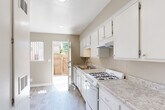 Located at 19007 Kittridge St in Reseda, Los Angeles, this 2-bedroom, 1-bathroom unit offers a practical and well-organized single-floor layout. The galley-style kitchen is a standout feature, equipped with white cabinetry, granite-style countertops, a gas range, dishwasher, and an under-cabinet range hood. Light wood-look flooring runs throughout the kitchen, which benefits from natural light through a side window and direct access to an outdoor area via a rear door — ideal for added ventilation and convenience.

The spacious primary bedroom features a textured ceiling, a wall-mounted HVAC unit, and a large window that brings in natural light. The light wood-look flooring continues throughout, creating a cohesive aesthetic. A dedicated closet offers built-in shelving with corner shelves, maximizing storage options.

The bathroom is cleanly appointed with a full tub-shower combination, white tile surround, grab bars for added safety, a vanity with sink, and matching wood-look flooring. Neutral warm-gray wall tones are consistent throughout the unit, lending a calm and cohesive ambiance. This efficiently designed home offers comfortable everyday living in a convenient Los Angeles location.