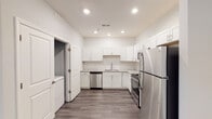 Located in Burlington, NC, this single-floor unit offers a thoughtfully designed layout with modern finishes and a clean, contemporary aesthetic. The kitchen is a standout feature, outfitted with crisp white shaker-style cabinetry, light stone countertops, and a full suite of stainless steel appliances including a refrigerator, range, and dishwasher. Wood-look plank flooring runs throughout the kitchen and main living areas, lending warmth and continuity to the space. The bedrooms are finished with soft wall-to-wall carpeting in a neutral tone, complemented by light blue-gray walls that create a calm and restful atmosphere. Each bedroom includes ceiling fans and features generous closet space with double-door configurations. Natural light filters in through windows with blinds, offering views of the surrounding neighborhood. The bathroom is finished in a clean, all-white palette, featuring a full soaking tub with overhead shower, chrome fixtures, and a vanity with a light stone countertop and large mirror. Throughout the unit, white panel doors, recessed lighting, and consistent neutral tones contribute to a cohesive and move-in-ready environment well-suited for comfortable everyday living.