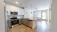 This thoughtfully designed one-bedroom, two-bathroom unit in Rowlett, TX offers a modern living experience with high-quality finishes throughout. The open-concept kitchen serves as the heart of the home, anchored by a central island with granite countertops, an undermount sink, and stylish pendant lighting. Two-toned cabinetry — white uppers and gray lowers — pairs elegantly with a subway tile backsplash, while a full suite of stainless steel appliances, including a range, microwave, refrigerator with ice maker, and dishwasher, completes the space. Wood-look flooring flows throughout the main living areas, leading to a bright living area with a ceiling fan and natural light from large windows and a glass door. The spacious bedroom features plush carpet, a ceiling fan, and a window that brings in natural light. It connects to a well-organized walk-in closet with built-in shelving and dual hanging rods. The primary bathroom impresses with a dual-sink granite vanity, gray cabinetry, and a large walk-in shower enclosed by a frameless glass door and finished with floor-to-ceiling tile. A second bathroom provides additional convenience, rounding out this refined and functional residence.