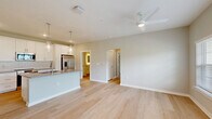 Located at 4434 Cobalt Brook Boulevard in Lutz, FL, this thoughtfully designed 1-bedroom, 2-bathroom residence offers a well-organized single-floor layout. The open-concept living area seamlessly connects the living room, dining area, and kitchen, all finished with light-toned hardwood flooring and neutral walls that create a bright, airy atmosphere. Ceiling fans are installed throughout, contributing to comfort and airflow.

The kitchen is a standout feature, boasting crisp white shaker cabinetry extending to the ceiling, a classic white tile backsplash, and grey quartz countertops. A central island with an undermount sink and pendant lighting serves as both a prep space and gathering point. Stainless steel appliances, including a French door refrigerator, electric range, and built-in microwave, complete the space.

The generously sized bedroom receives abundant natural light through large windows with outdoor views, and is equipped with a ceiling fan. Three closets provide ample storage, including wire-rack shelving systems. A dedicated laundry room houses a full-size washer and dryer. A private balcony extends the living space outdoors. The hallway connects all areas efficiently, rounding out this clean, modern, and functional residence.