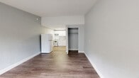 Located at 9135 Talina Lane in Temple Terrace, Florida, this studio unit offers an efficient, single-floor layout that maximizes every square foot. The open-concept living area flows seamlessly into the kitchen, creating a cohesive and functional space. Light wood-style vinyl plank flooring runs throughout the living and kitchen areas, providing a clean, contemporary look that contrasts nicely with the soft gray-toned walls and bright white trim.

The kitchen is well-equipped with white cabinetry, granite-style countertops, a coil-burner electric range, and a full-size refrigerator. A skylight-style overhead light fixture brightens the kitchen area, adding to the overall sense of openness. White appliances and cabinetry give the kitchen a crisp, tidy appearance.

Adjacent to the living area is a dedicated closet with a built-in hanging rod, offering practical storage. The bathroom features a white vanity with a single sink and mirror, a toilet, and textured walls with brushed nickel grab bars and towel hardware — a detail that adds both style and accessibility. The flooring in the bathroom continues the wood-style plank theme, maintaining visual consistency throughout the unit.

The textured ceilings and neutral color palette create a calm, move-in-ready atmosphere, making this a practical and well-appointed studio in Temple Terrace.