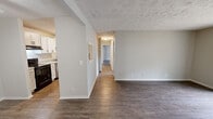 Located at 7700 Gleason Dr in Knoxville, Tennessee, this single-floor, two-bedroom, two-bathroom residence offers a well-designed layout with modern finishes throughout. Durable hardwood-style flooring runs continuously through the main living areas, complemented by neutral-toned walls and textured ceilings that add subtle character to each room.

The galley-style kitchen is a standout feature, showcasing crisp white shaker cabinets with matte black hardware, light granite-style countertops, and a full suite of stainless and black appliances including a range, dishwasher, and refrigerator. The kitchen connects conveniently to the laundry area, which includes washer hookups and built-in shelving.

The spacious living area benefits from a sliding glass door that opens to an outdoor space, filling the room with natural light and offering views of the surrounding grounds. A ceiling fan adds to the comfort of the connected dining or flex area.

The generously sized primary bedroom provides ample room and includes access to a dedicated closet. The second bedroom is equally well-proportioned with its own closet space. Both bathrooms feature white vanities with granite-style counters, tiled tub-shower combinations, and coordinating black hardware. A hallway connects all rooms in a practical, flowing arrangement.